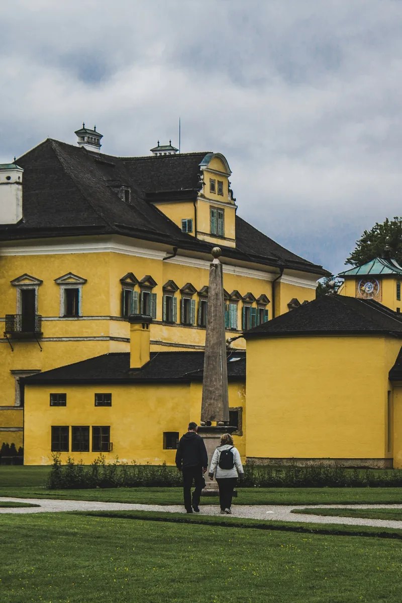 Visitors laughing as hidden jets rise from the stone trick-fountain gardens at Hellbrunn Palace, Salzburg